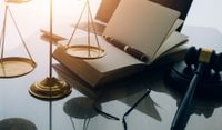 Libro jurídico junto a un mazo de juez y balanza